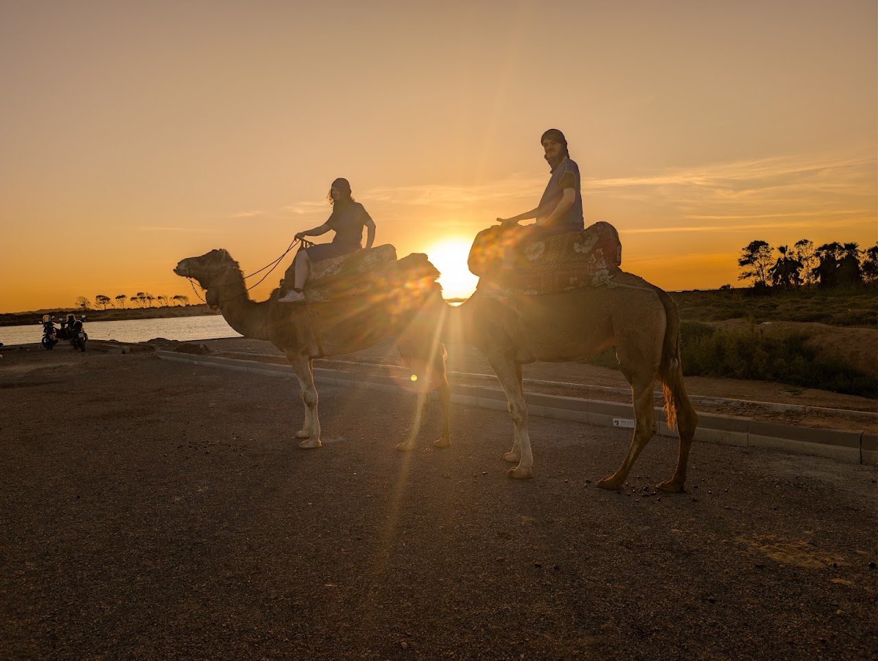 Two riders on camels silhouetted against the setting sun near Agadir