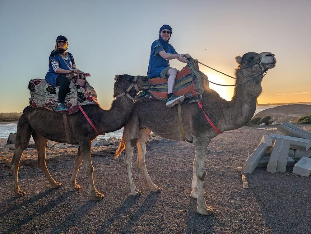 Two guests on camels photographed at golden hour